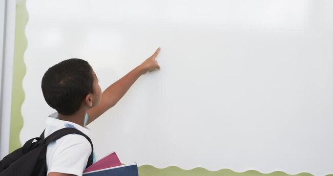 In school, young biracial male student pointing at something, copy space