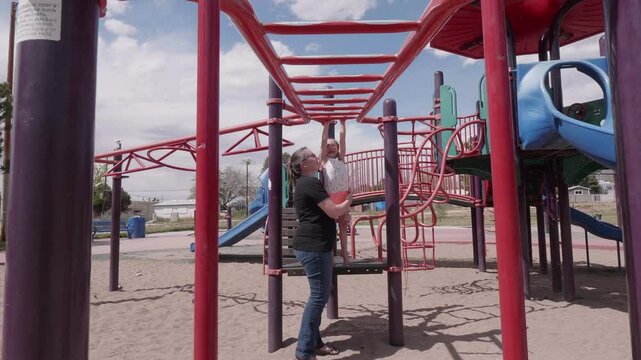Mother Teaching Child How to Use the Monkey Bars
