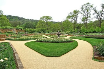 Classic English Garden with Rose Bushes: A symmetrical garden with lush green lawns, perfectly pruned rose bushes in bloom, winding gravel paths, and a fountain centerpiece.