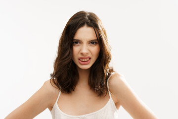 Young brunette woman in a white light top posing against a white background, expressing emotions...