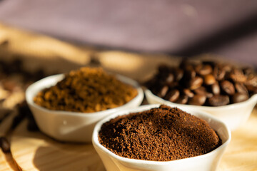 Close up of small porcelain bowls with different types of coffee. beans, ground  and instant, on a...