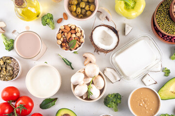 Plant based keto food background with low carb vegan keto diet ingredients, healthy vegetarian fat and protein source. Assortment green vegetables, nuts, legumes, oil, coconut, nuts, peanut butter