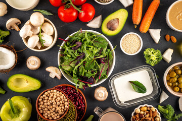 Plant based keto food background with low carb vegan keto diet ingredients, healthy vegetarian fat and protein source. Assortment green vegetables, nuts, legumes, oil, coconut, nuts, peanut butter