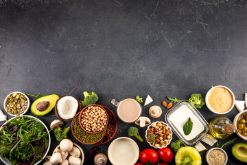 Plant based keto food background with low carb vegan keto diet ingredients, healthy vegetarian fat and protein source. Assortment green vegetables, nuts, legumes, oil, coconut, nuts, peanut butter