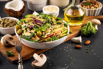 Plant based keto food, low carb vegan salad various green vegetables, avocado, arugula, spinach, lettuce, with feta cheese, nuts, seeds, peanut butter, avocado and olives