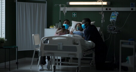 Young parents in masks sit next to their seriously ill daughter in intensive care.