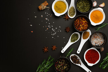 Food cooking ingredients background with various spices in bowls on dark table top view