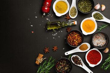 Food cooking ingredients background with various spices in bowls on dark table top view
