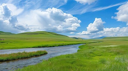 Fototapeta premium A beautiful green field with a majestic mountain, a clear river and a vast sky in the background. The idyllic and serene natural scenery creates a peaceful and charming atmosphere.