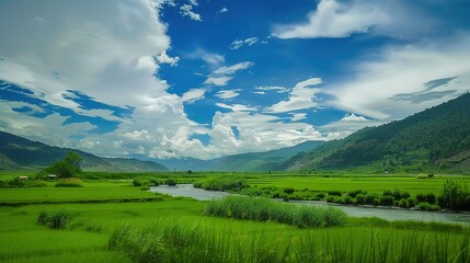 A beautiful green field with a majestic mountain, a clear river and a vast sky in the background. The idyllic and serene natural scenery creates a peaceful and charming atmosphere.