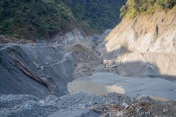 A landslide blocking a river and forming a temporary dam, with water pooling behind the debris