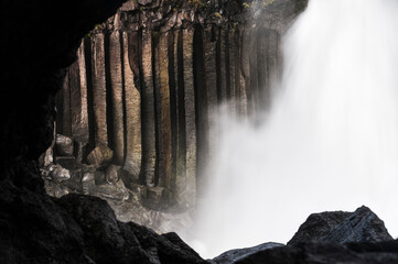 Majestic waterfall cascades over hexagonal basalt columns in a misty natural setting
