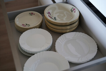 A deep drawer in a kitchen unit where various types of plates are placed.