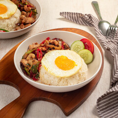 A hearty meal featuring stir-fried chicken with bell peppers, rice, and a sunny-side-up egg, garnished with fresh cucumber slices
