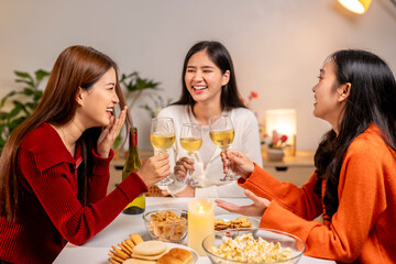 Three women are sitting at a table, laughing and drinking wine