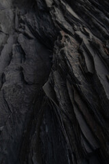 Black rock background. layered mountain surface close up. dark stone texture. cracked layers of slate