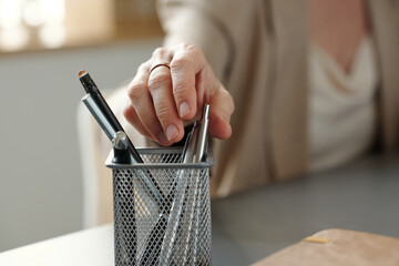 Focus on hand of experienced female lawyer or broker taking silver pen from bin before signing contract