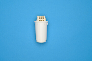 Dirty green replacement filter cartridge for drinking water purification on blue background, top view. Water pollution concept, untimely replacement of water filters, water purification. Copy space