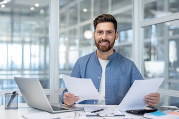 Portrait of successful financier doing paperwork, man with contracts and reports smiling and...