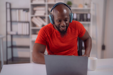 Young african american businessman wearing a red t-shirt is smiling while having a video call on...