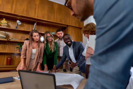 Diverse group of architects and engineers examining blueprints on a table during a productive office meeting, fostering collaboration and innovation