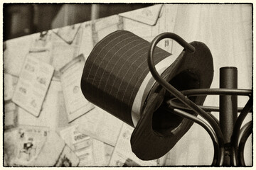 An image of a top hat hanging on a coat rack, stylized to look like an old black and white photograph