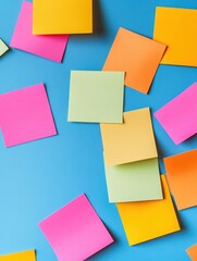 Fototapeta premium Colorful sticky notes scattered on a blue surface, ideal for brainstorming and creative ideas in office environments.