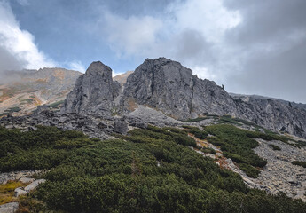 A mountain with a cloudy sky in the background. The mountain is covered in green vegetation