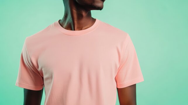 person in a blank pastel pink t-shirt in front of a mint green background, plain pink t shirt mockup