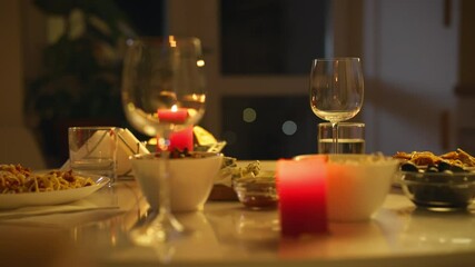 A cozy dining table adorned with candles and elegant glassware set for a romantic dinner. Delicious gourmet dishes are served, creating an inviting atmosphere in the evening