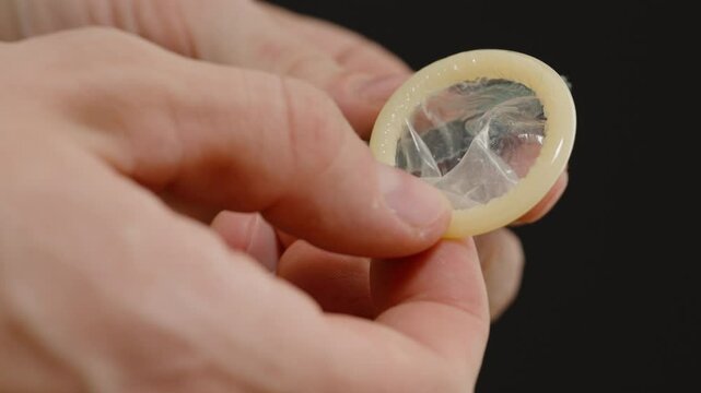 Hands Carefully Removing a Condom from Its Packaging, Highlighting Preparation and Emphasizing the Importance of Safe Sex Practices