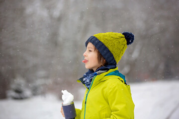 Sweet toddler boy, playing with snow on playground