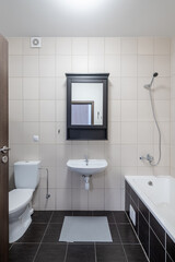 Modern Home Bathroom Interior with Sink, Bathtub, and Contemporary Design. Bright and clean bathroom interior featuring a sink, bathtub, toilet, mirror, and minimalistic tiling and decor.