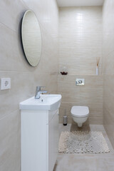 Modern, minimalist bathroom with beige tile, white vanity, and toilet. Clean and bright design. Home Interior