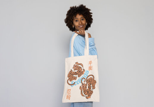 Totebag held confidently by a smiling black woman in a casual outfit, perfect for customization.