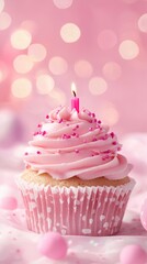 A pink cupcake with a lit candle on top