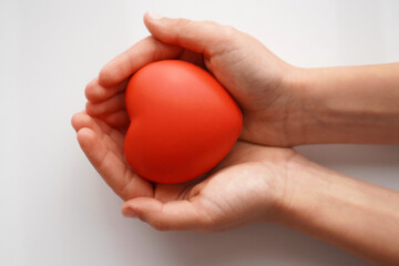 hands of a child in position to give or receive a red heart