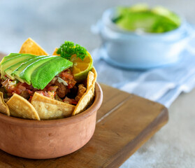 Traditional Costa Rican Chifrijo with Avocado and Salsa in a Rustic Clay Bowl on a Wooden Board
