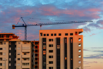 Apartment building construction site with crane at sunset
