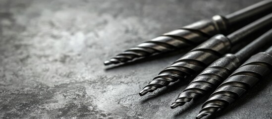 Industrial metal drills arranged on a textured gray surface with ample space for custom text or branding messages.