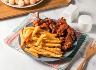 Fried Chicken thighs, French fries and potato balls served in plate with fork isolated on napkin side view of taiwan food