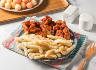 Fried Chicken thigh, crispy breadsticks, sweet and sour and potato balls served in plate with fork isolated on napkin side view of taiwan food