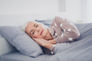 Elderly woman peacefully asleep in polka dot pajamas enjoying a restful morning in her cozy bedroom