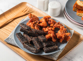 Fried Chicken thigh, rice blood cake and potato balls served in plate with fork isolated on napkin side view of taiwan food