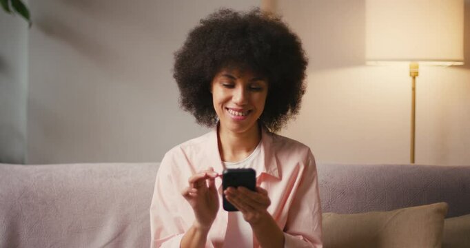 Hispanic woman with afro hair scrolls social media on phone