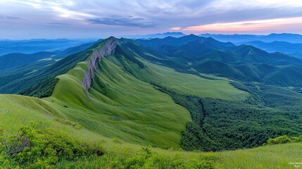Obraz premium Majestic mountain range at sunset, green valley, distant peaks. Scenic landscape for travel posters