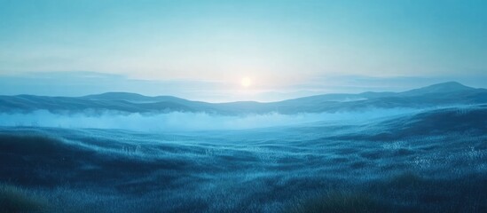 Fototapeta premium Serene summer tundra landscape with blue fog-covered hills and a soft morning sun creating vast empty space for text or captions.
