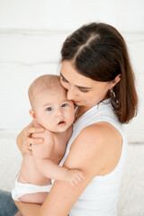 mom with a baby, an international family, a Caucasian mom with an Asian baby in her arms in the bedroom gently hugs him holding him in her arms, a place for text