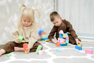 Fototapeta premium Brother and sister play with blocks and cubes at home