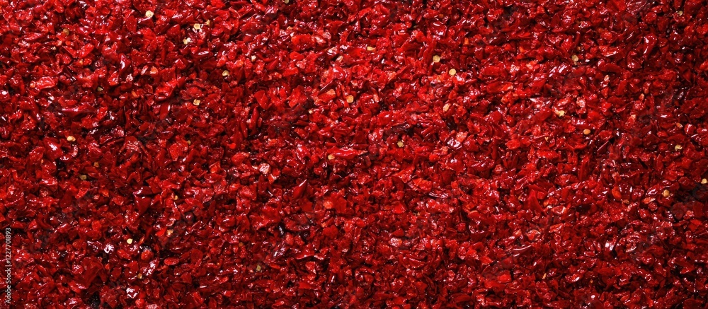 Aufkleber close up of vibrant red chili pepper flakes on textured background with ample empty space for text o